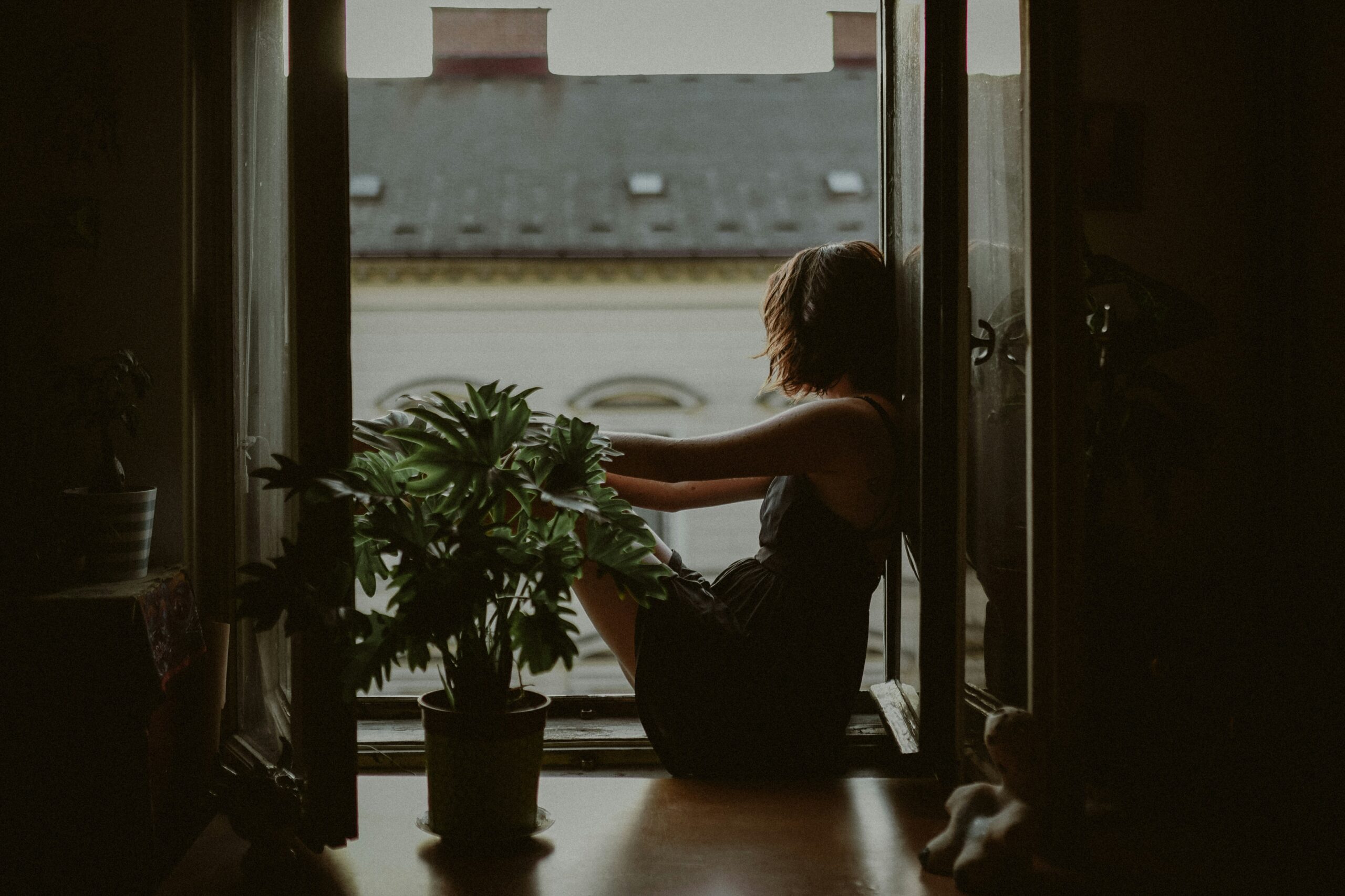 Woman sitting alone by a window during the no contact rule after a breakup